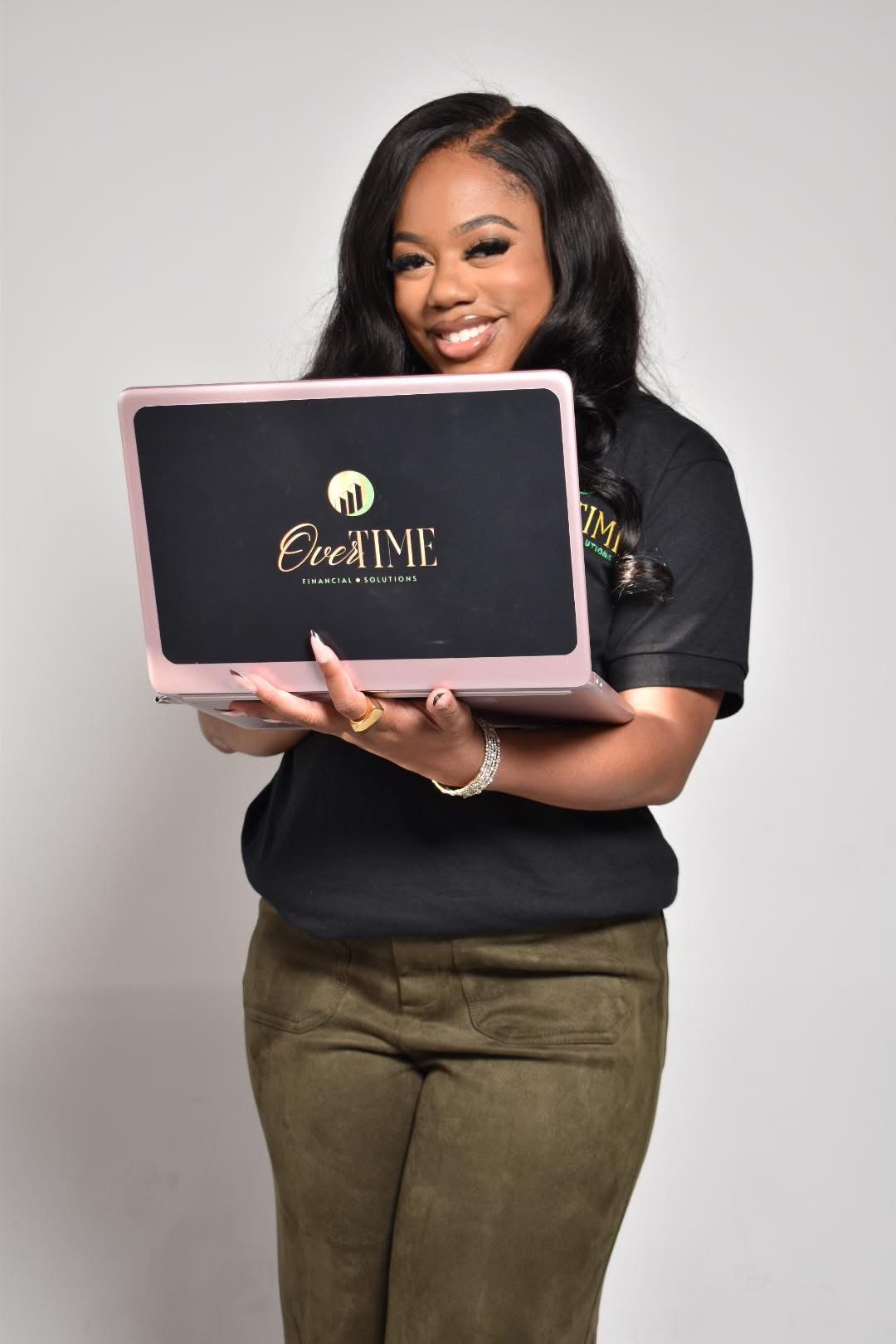 Taylor Philmore holding an Overtime Financial Solutions branded laptop